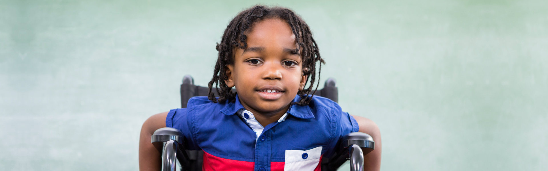 Portrait of handicapped boy against board in classroom